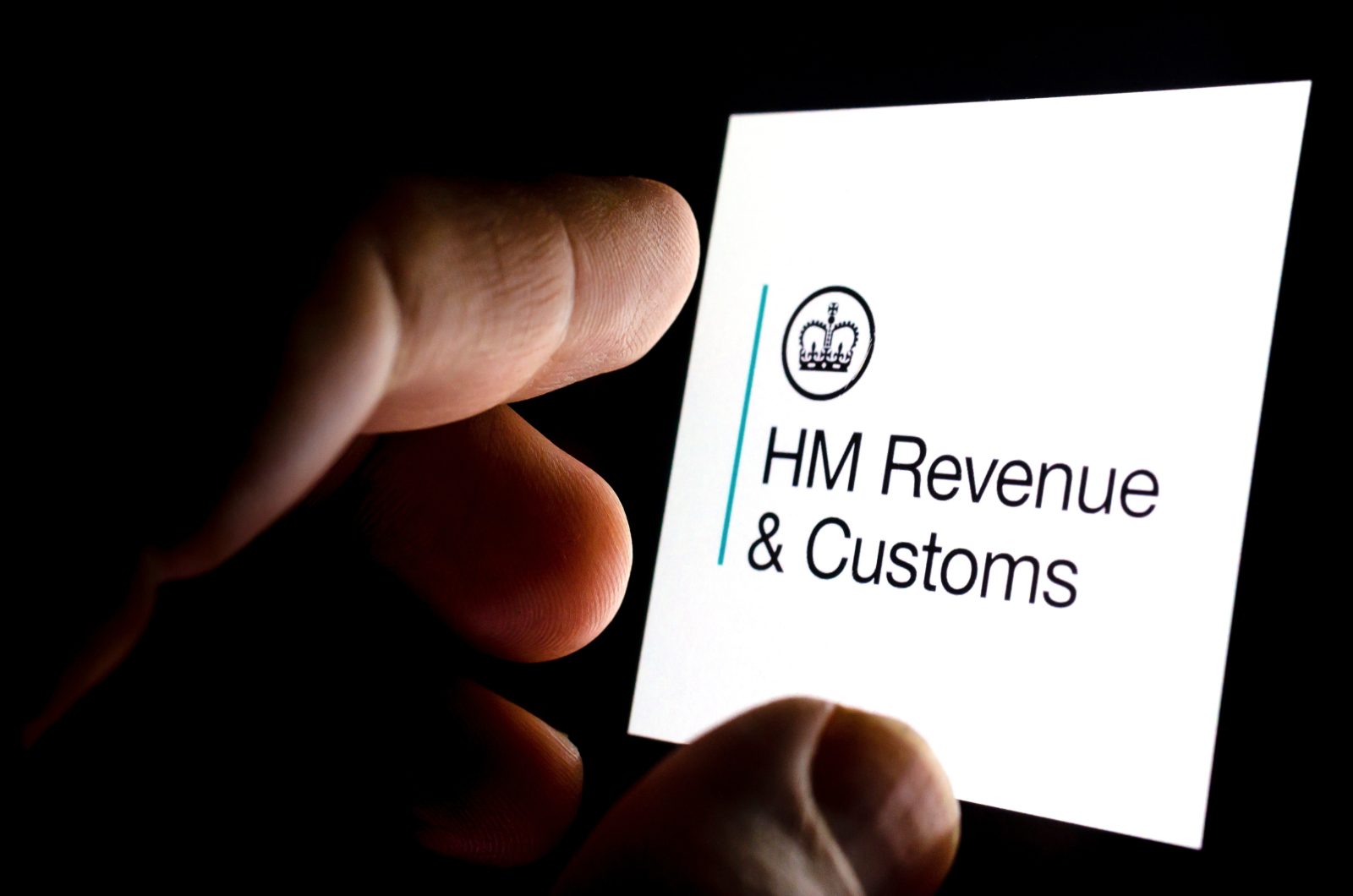 HMRC app logo on a glowing smartphone screen and the finger touc