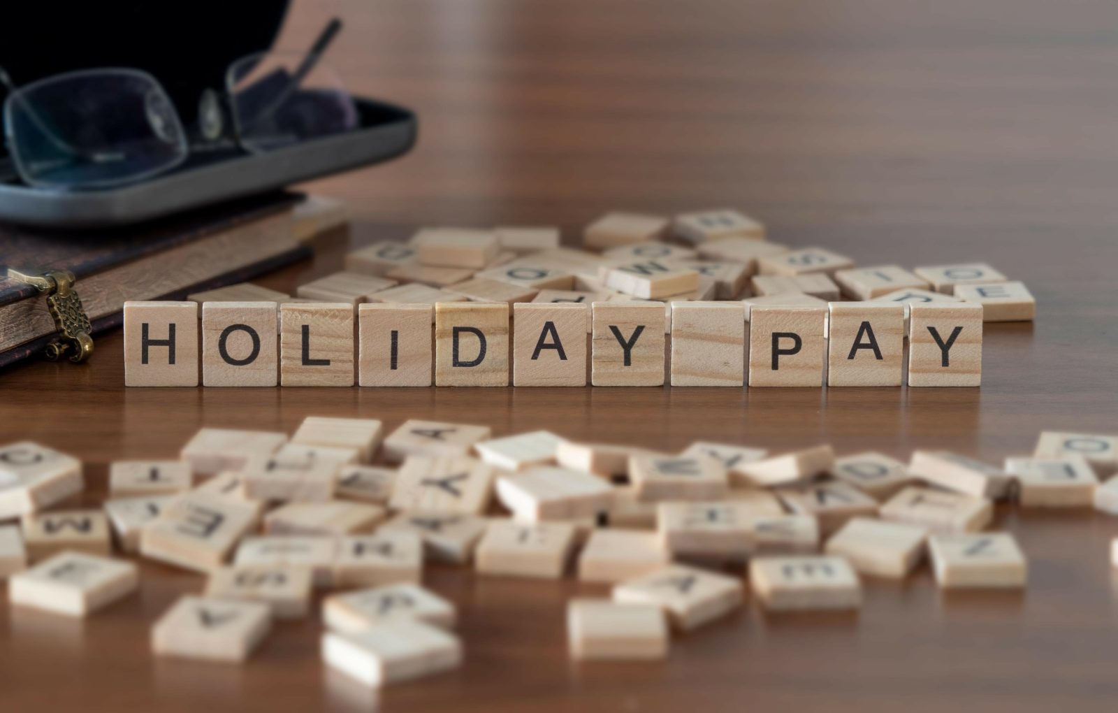Scrabble tiles spell out "Holiday Pay"