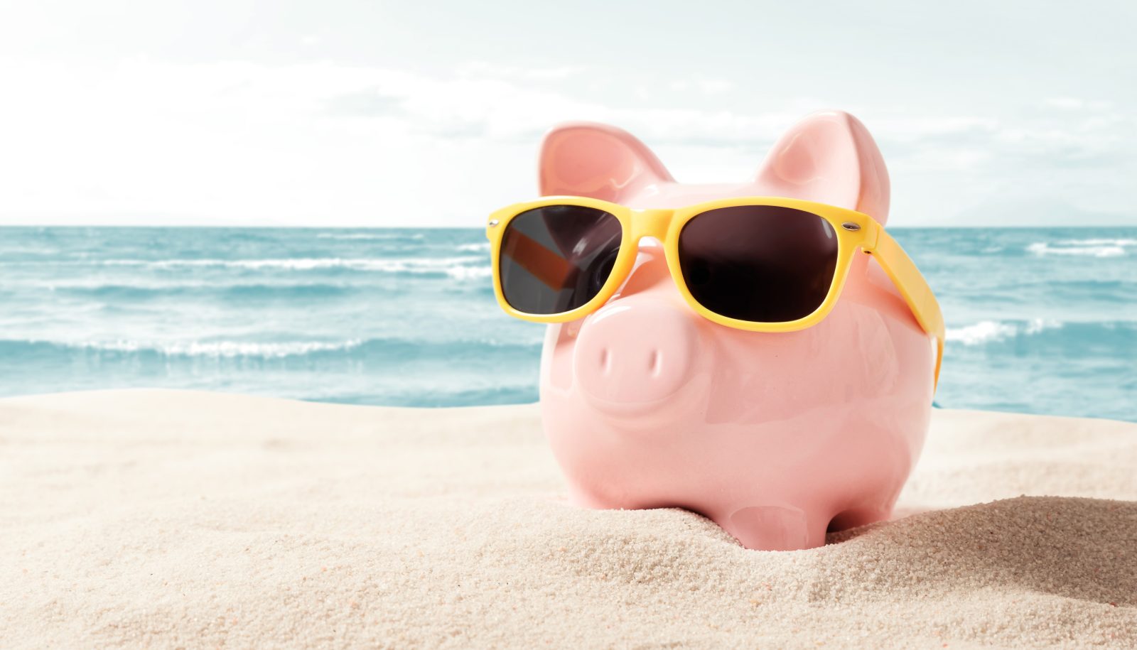 Piggy bank on beach in sunglasses