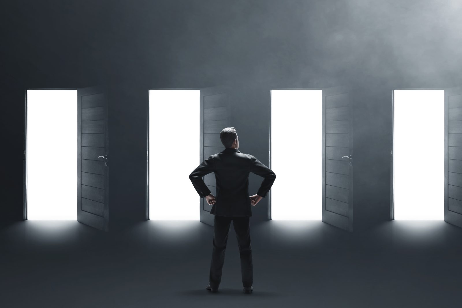 Man stands before four open doors, making a choice on which to enter.