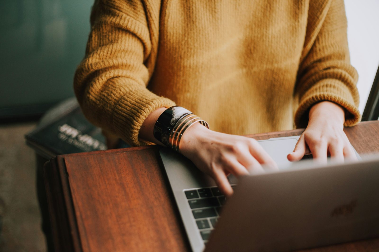Person in yellow jumper working at laptop